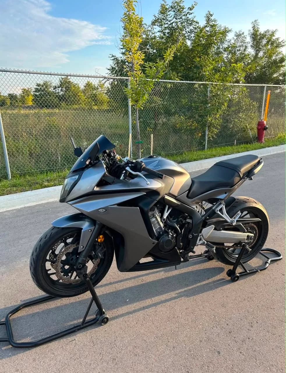2014 Honda CBR in gunmetal grey, left-hand side profile, on paddock stands